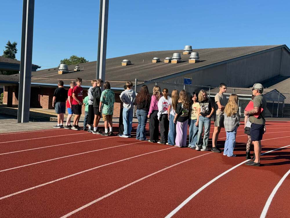 Students stand in a line outside on track