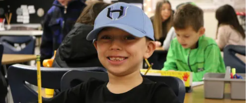 HSD student smiles in the classroom while working on an assignment.