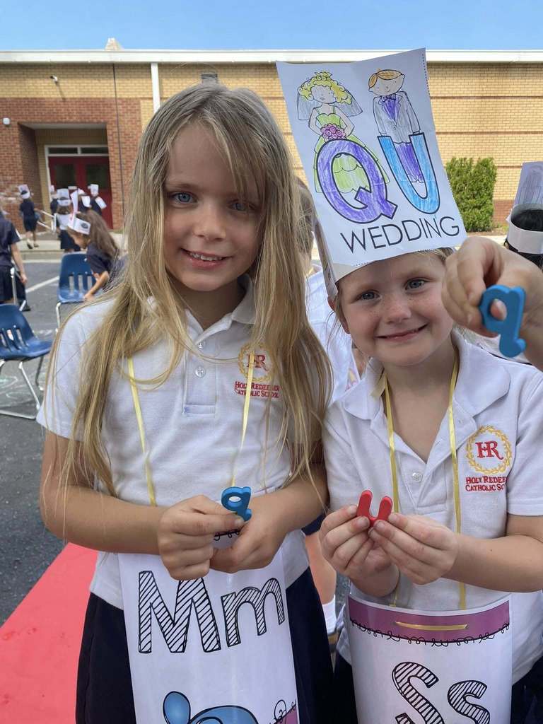 female kindergarten students holding letter signs 