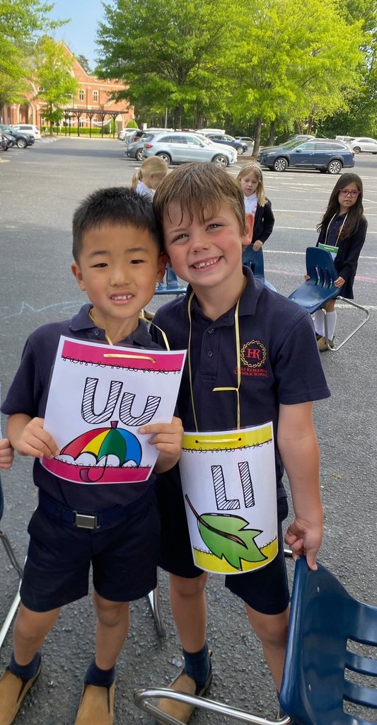 Two kindergarten students holding letter signs 