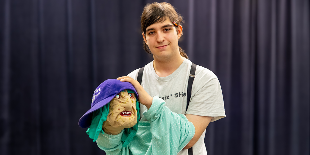 student poses with handmade puppet