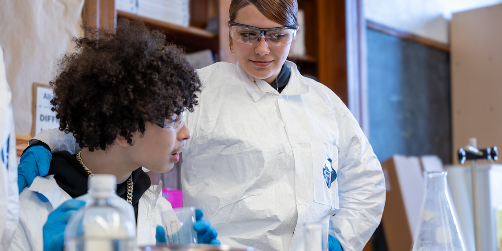 two students posing with lab coats in science class before an experiment