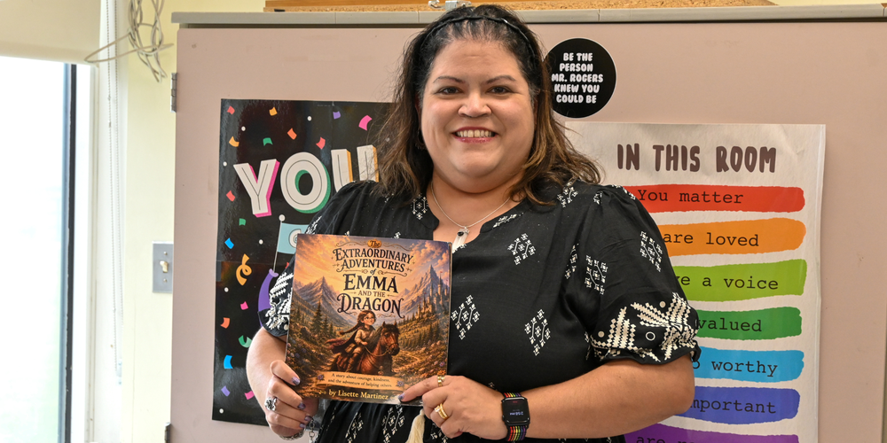 photo of teacher Lisette Martinez holding a copy of her first published children's book