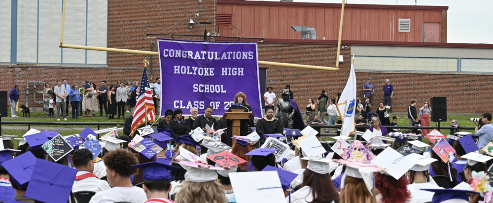 Class of 2025 graduation photo from behind the graduates, showing their purple and white caps
