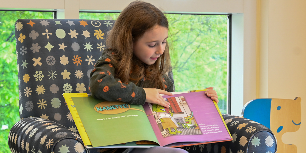 student sitting in chair reading a book