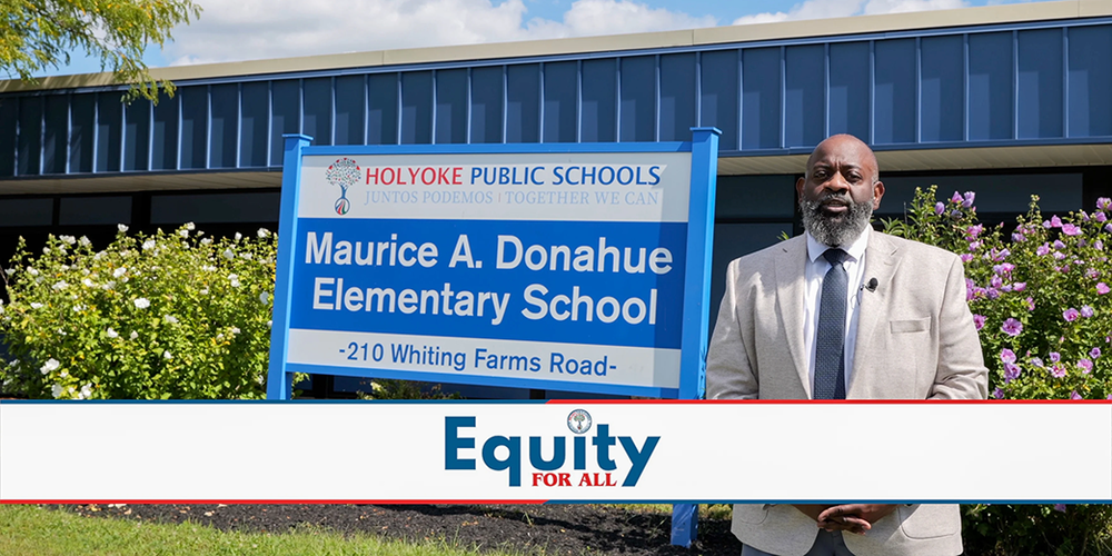 Chief of Student and Family Experience Steven Moguel next to Maurice A. Donahue Elementary School sign with overlay text: Equity for All