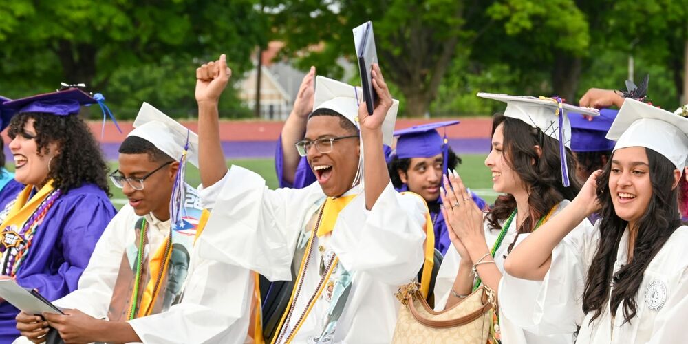 a group of graduates cheering after receiving their diplomas