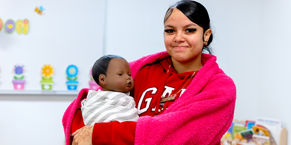 Student holding doll swaddled in a blanket