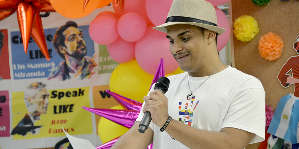 Student holding microphone in front of colorful display of balloons and posters