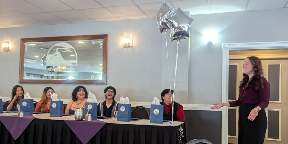 students sitting at table listening to a speech