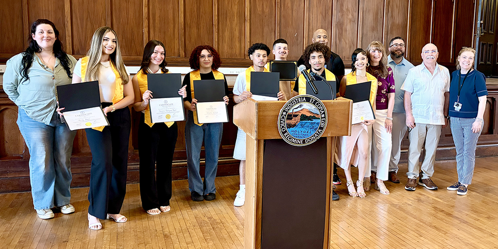 a group of students displaying folders with certificates of biliteracy