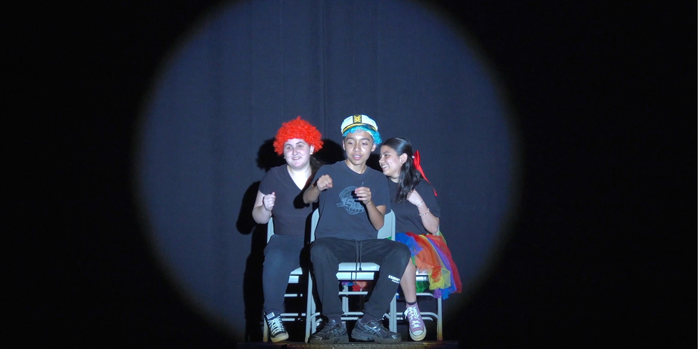 three students performing in a play on stage
