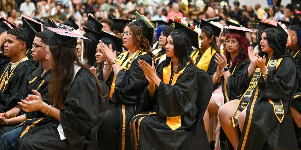 a group of graduates clapping after a speech