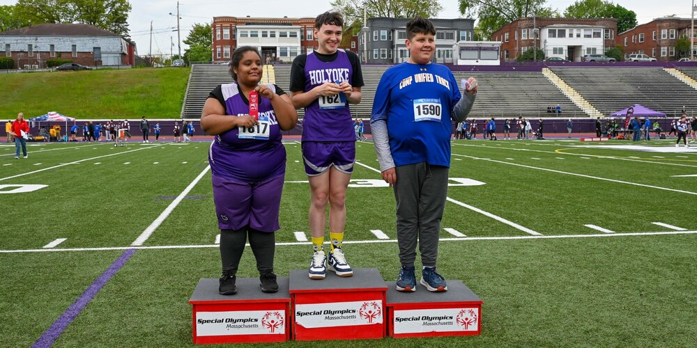 Three winning student athletes standing on podium