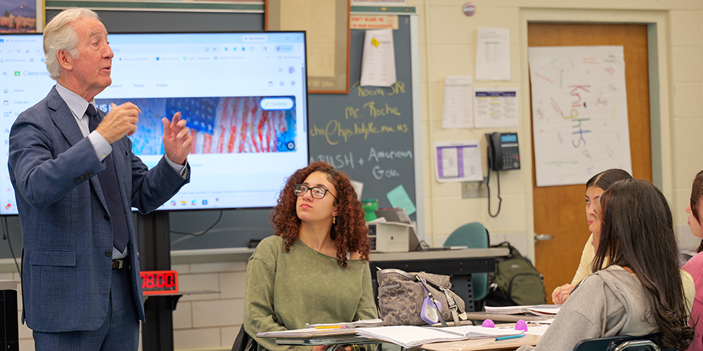Man speaks to a group of students at a desk