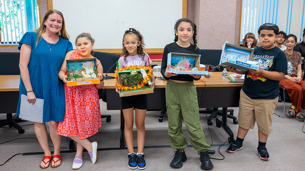 Students hold science displays built in shoe boxes