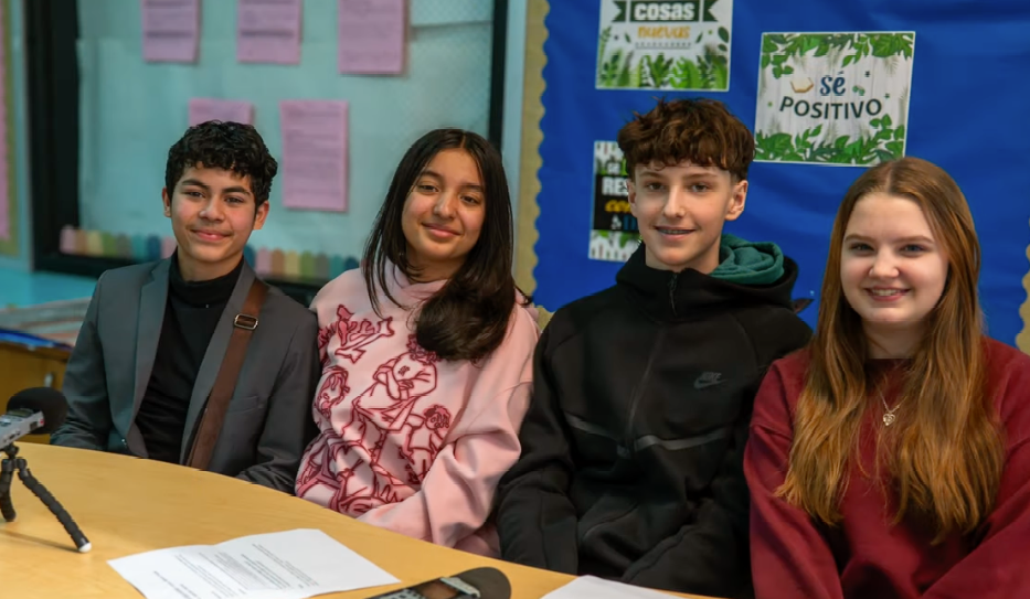 A group of middle school students look at the camera