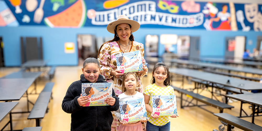 Author and three students holding copies of a children's book
