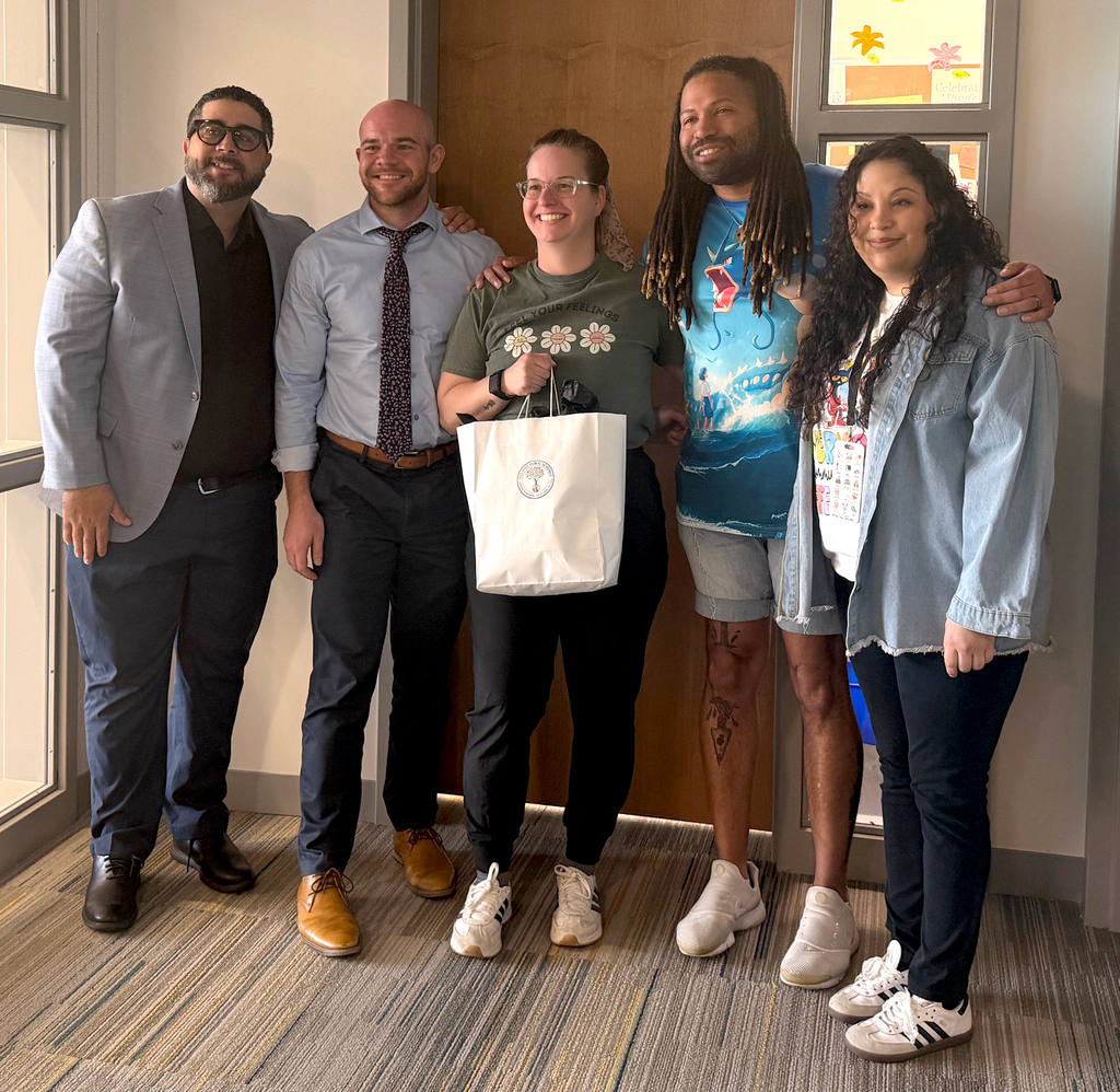 Teacher holding gift bag and standing with administrators and two parents