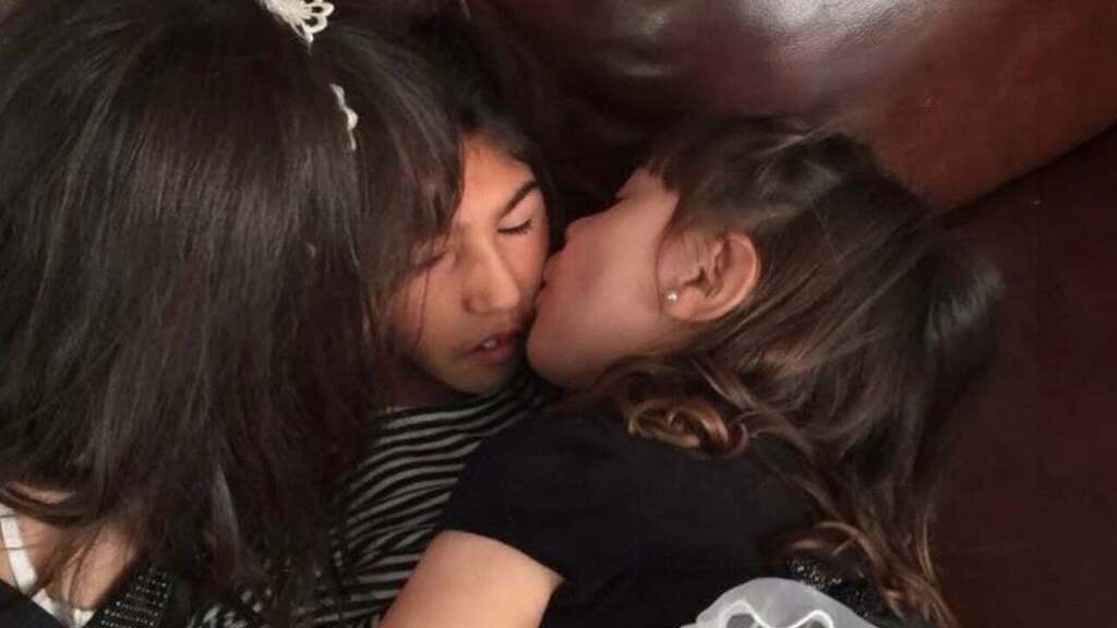 Genesis  beig kissed by her two sisters