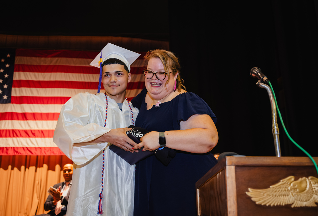 Graduate receiving his diploma and smiling.