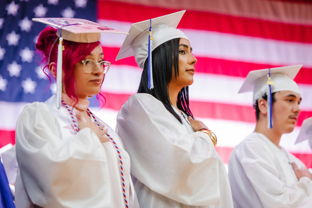 Graduates holding their hands on their heart during National Anthem