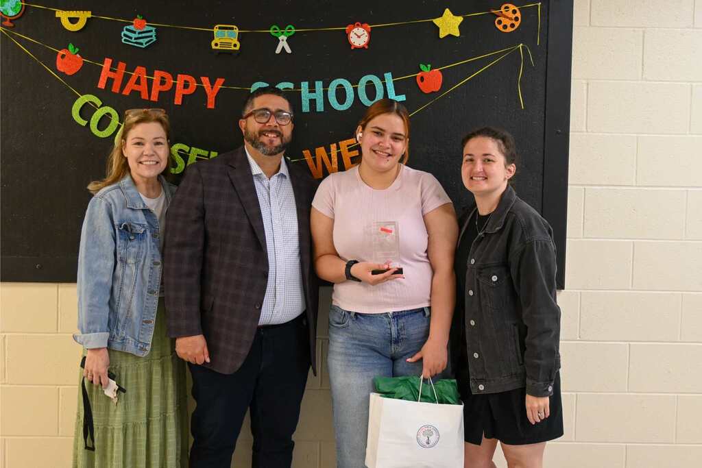 group of people posing together while someone holds up an award
