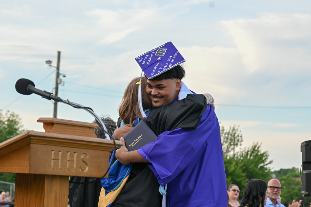 Graduate hugs his principle as he receives his diploma