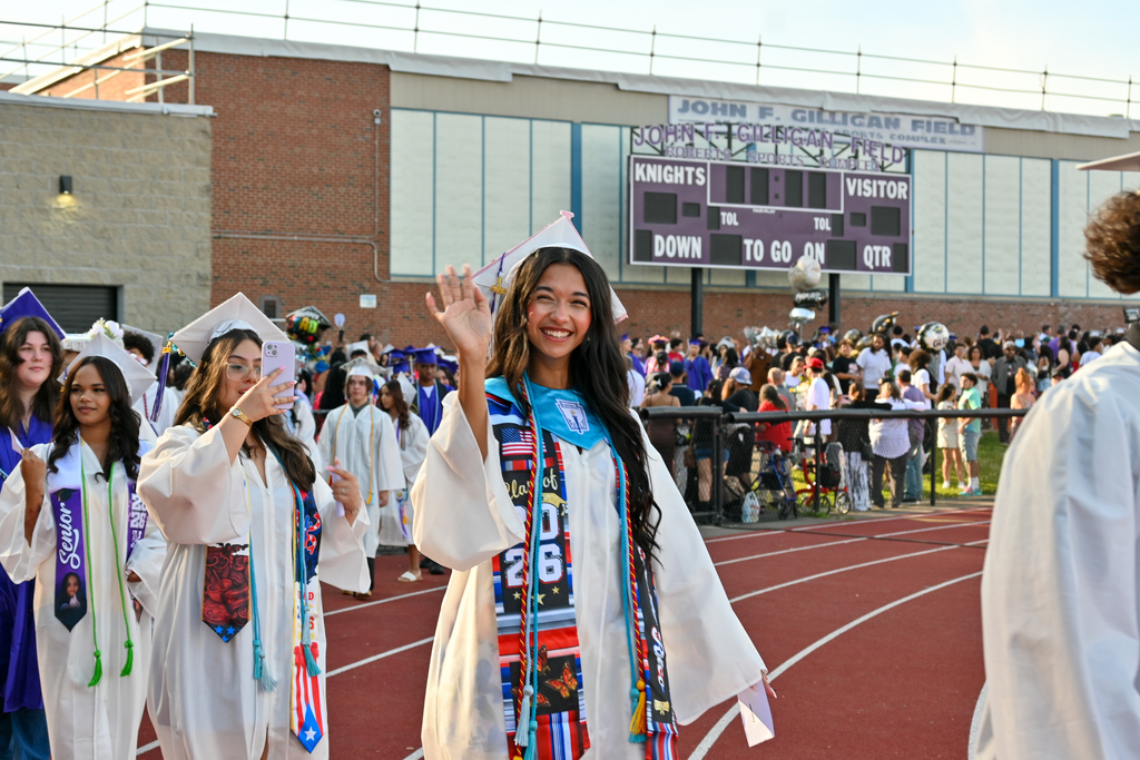 Graduate waves as she enters the field.