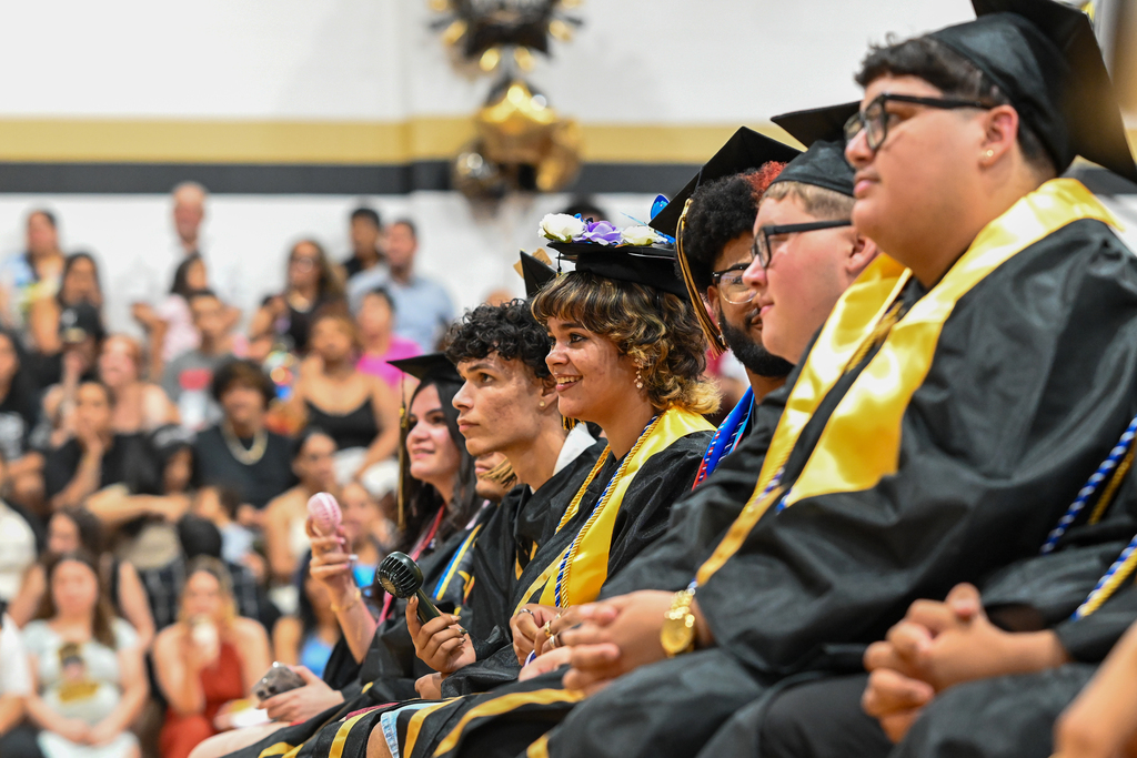 Graduates smile and look on.