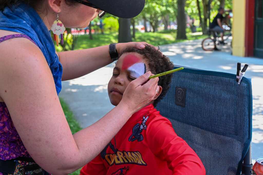 child sitting in a chair getting face paint