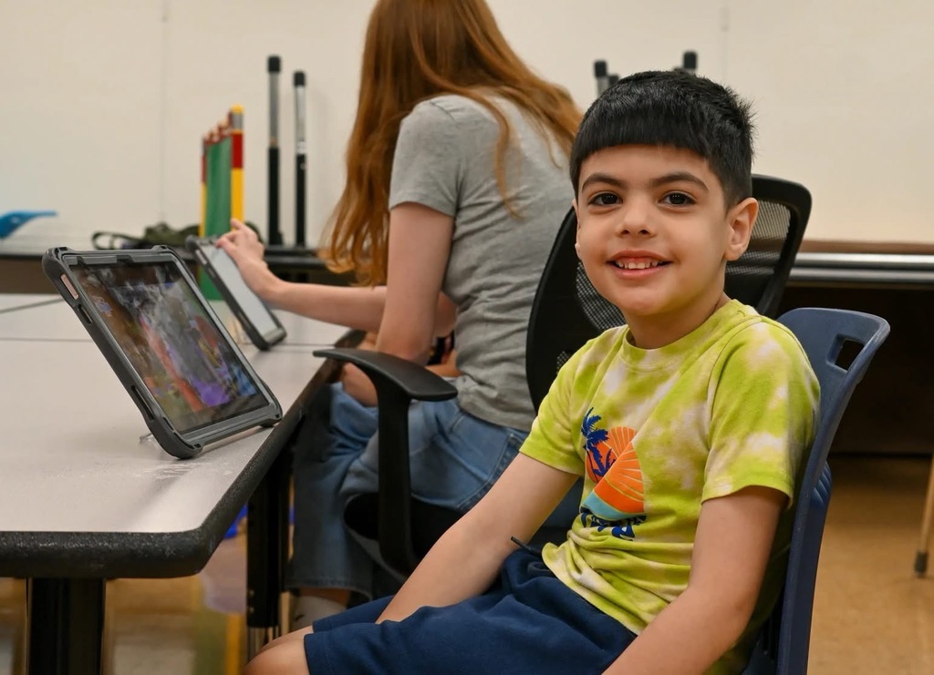 a student posed for a photo sitting at a table with his ipad