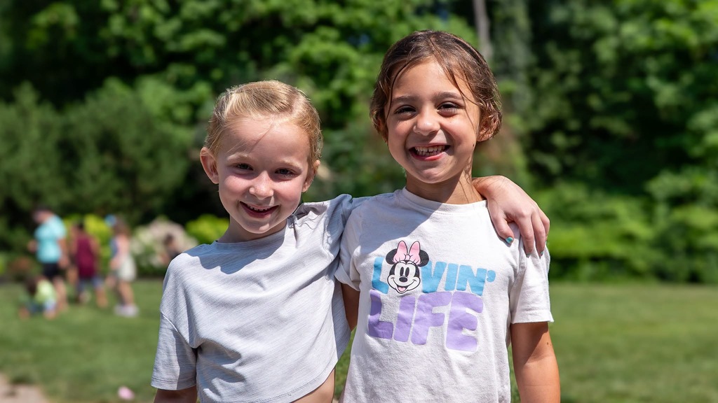 two girls posing for a photo in a field