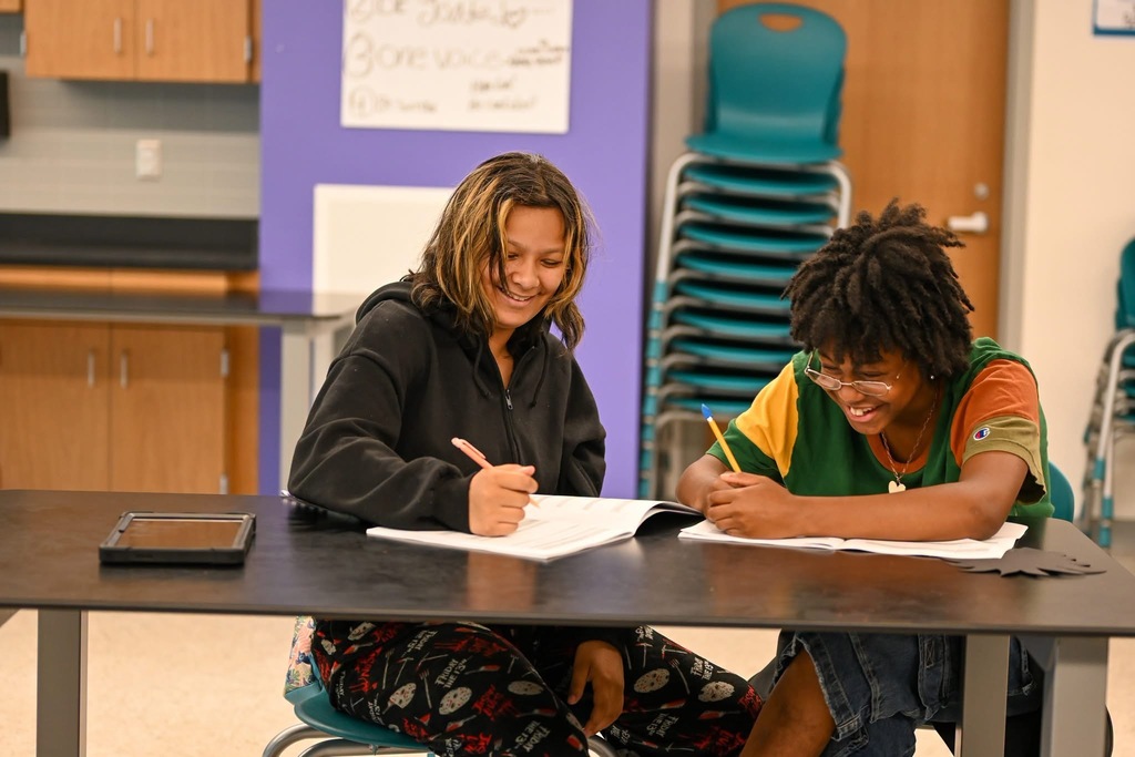 two students sitting at a table doing work