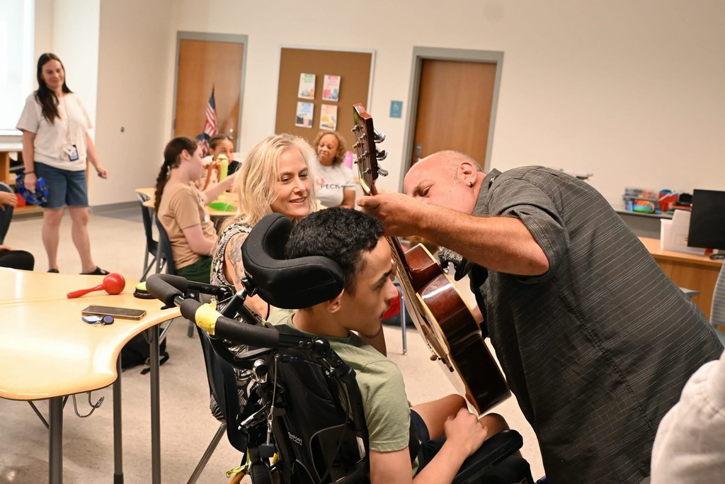 teacher having a student help play guitar