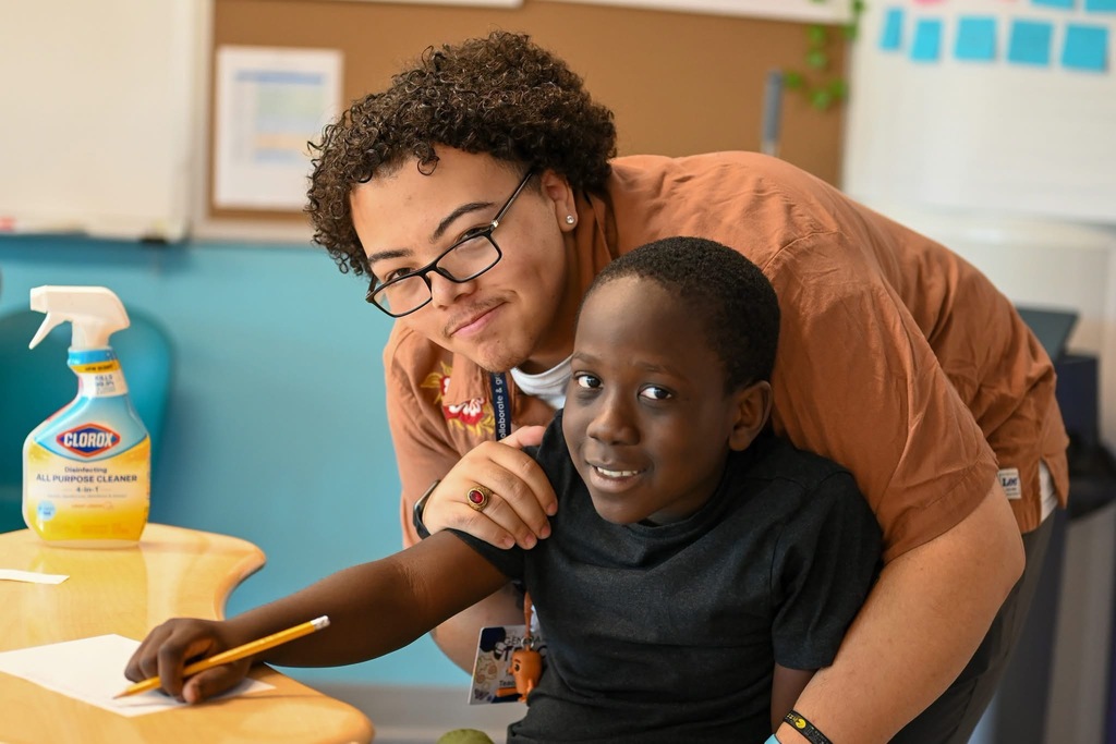 teacher and student pose for a photo while doing work