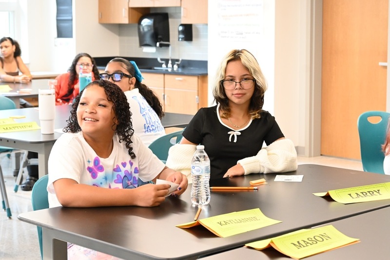 Two middle school students look at their teacher