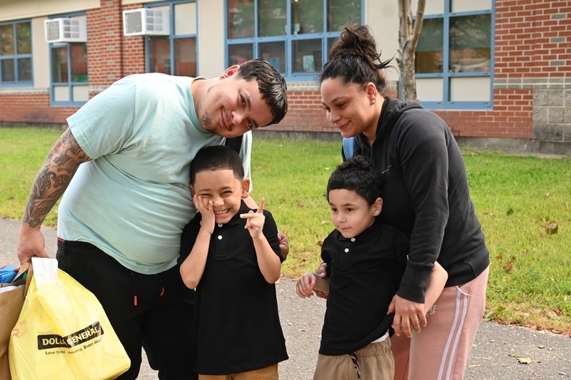 A family take a photo with their kids before school starts
