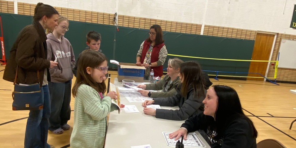 three teachers talk to a family that came to their station during family night while a translator looks on.