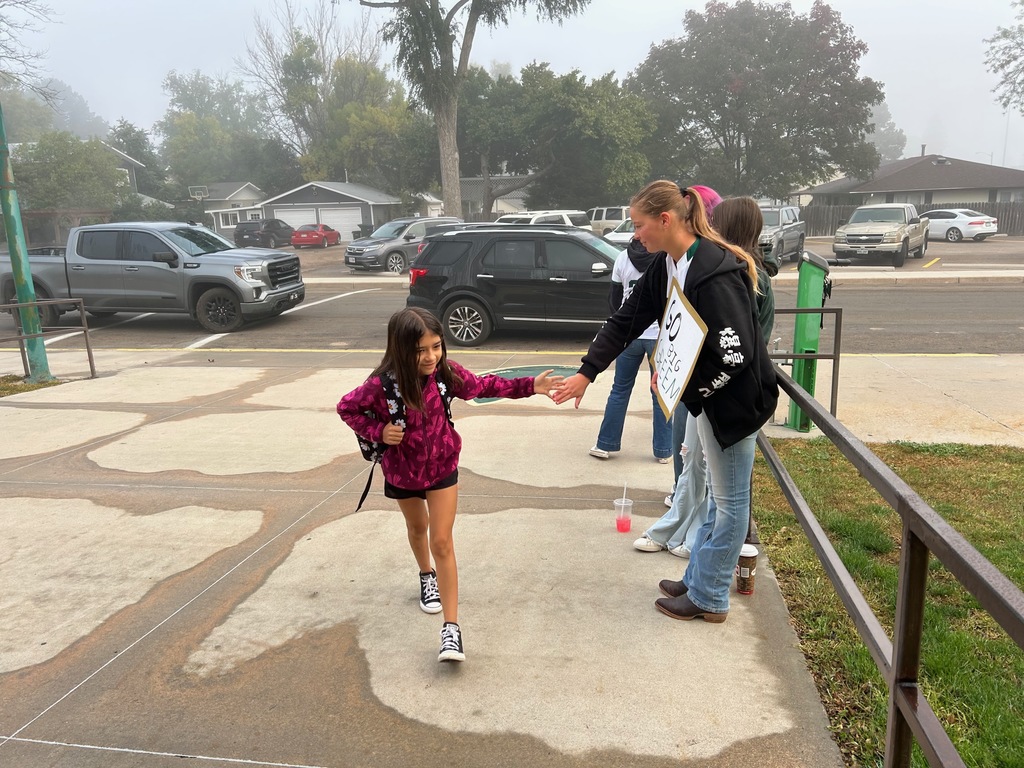 Elementary kid high fives softball player before school. 
