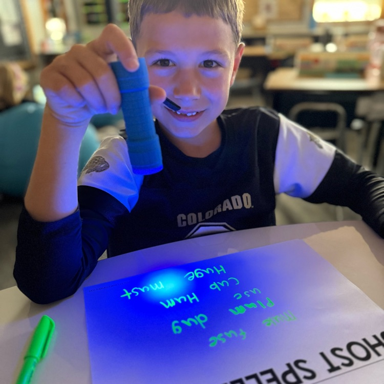 boy shines light on paper showing words 