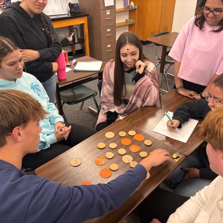 students sit around a table doing an assignment 