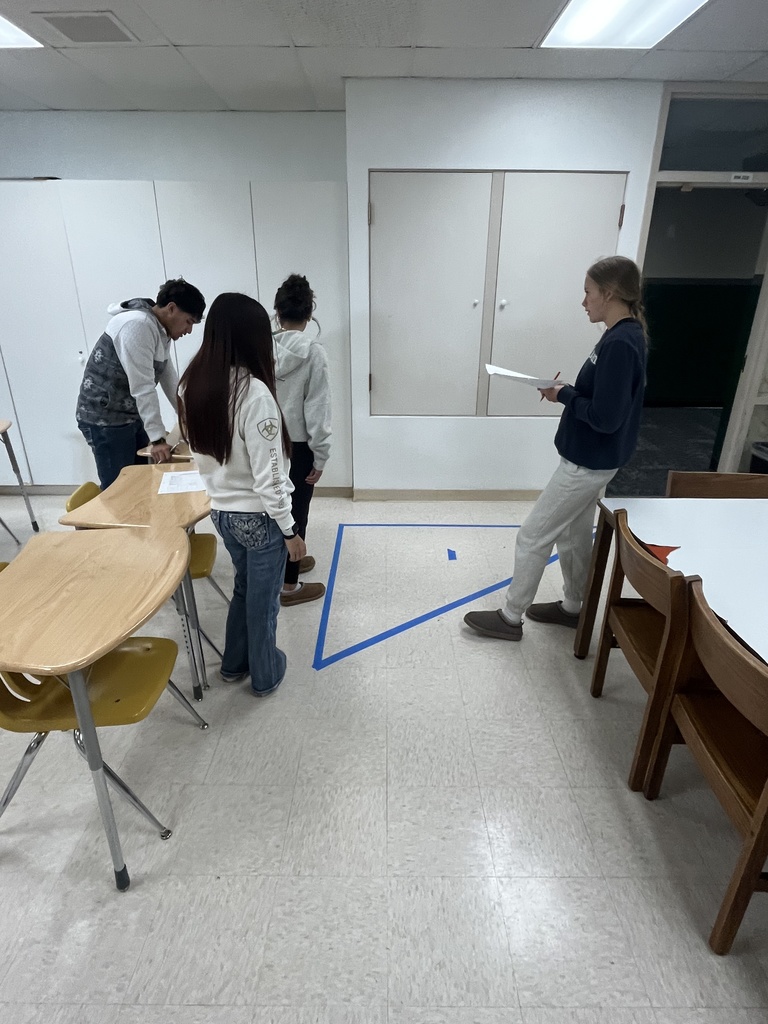 students looking at tape on the floor 