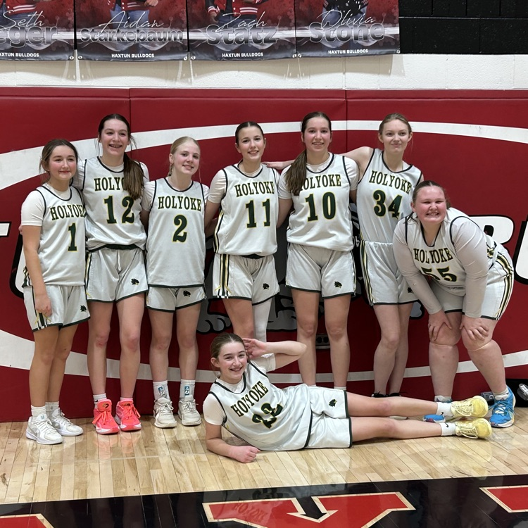 girls pose for a picture after winning a basketball game.