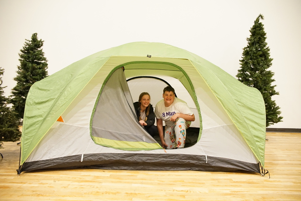 Two kids smile while sitting in tent