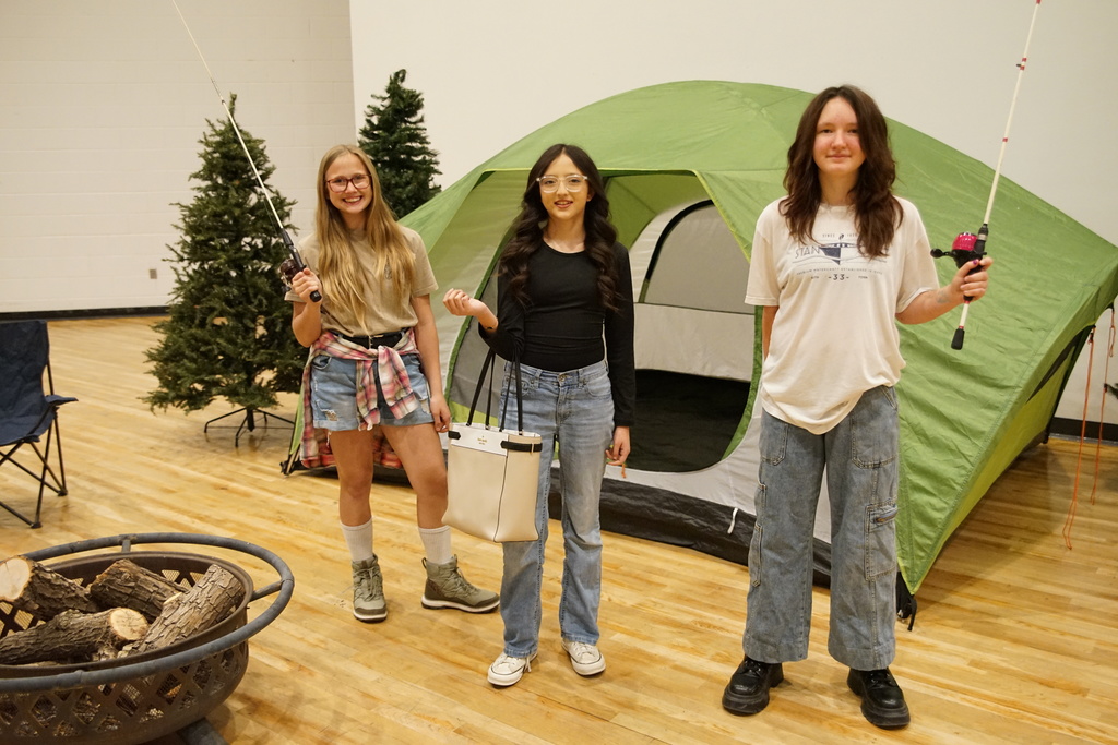 Three kids smile while holding fishing poles