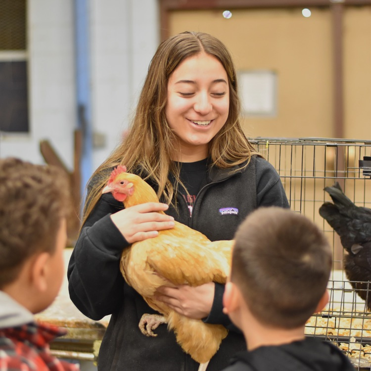 girl smiles while holding chicken