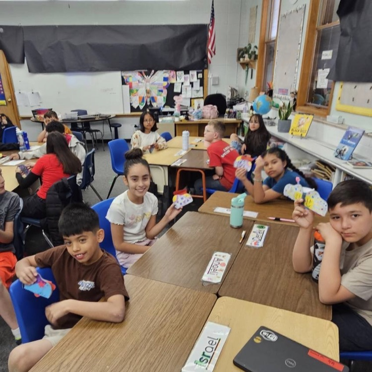 Students smile while holding up projects 