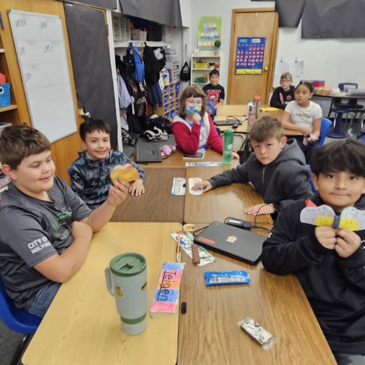 Students smile while holding up projects 