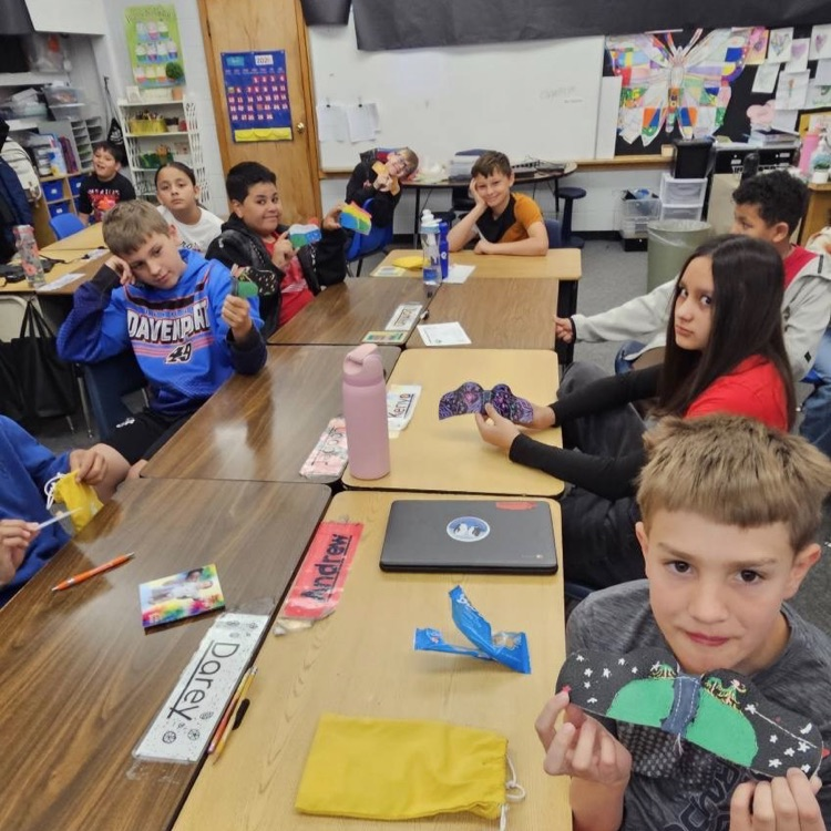 Students smile while holding up projects 